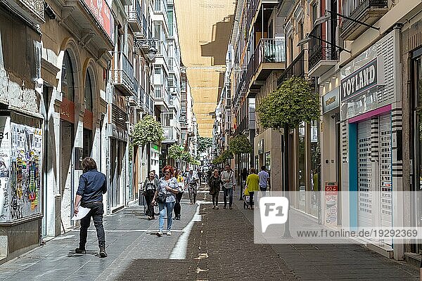 Granada  Spanien  27. Mai 2019: Menschen spazieren in einer charmanten engen Einkaufsstraße im historischen Stadtzentrum  Europa