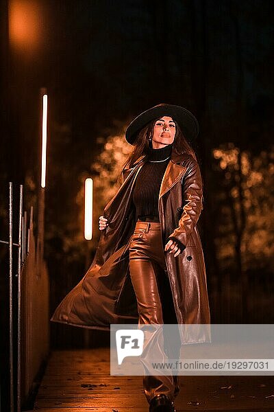 Hübsches kaukasisches Mädchen mit Hut geht nachts in einem Park spazieren. Wintermode und Lebensstil bei Nacht  vertikales Foto