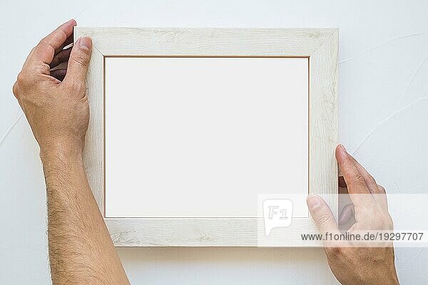 Mann s Hand Platzierung weißer Bilderrahmen Wand
