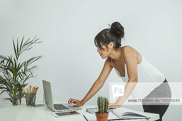 Junge Geschäftsfrau  die im Stehen mit einem Laptop arbeitet