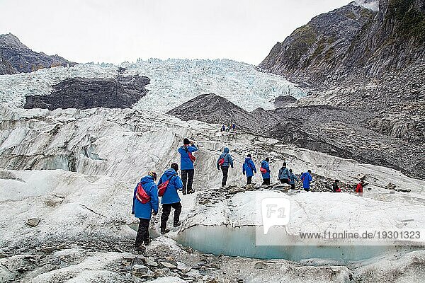 Franz Josef  Neuseeland  22. März 2015: Eine Gruppe von Touristen wandert auf dem Franz Josef Gletscher in Richtung eines Hubschraubers  Ozeanien