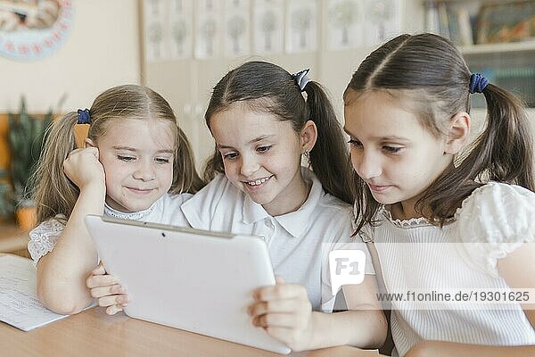 Fröhliches Mädchen benutzt Tablet im Klassenzimmer