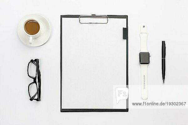 Kaffeetasse Brille intelligente Uhr Stift leeres Papier Zwischenablage weißer Schreibtisch