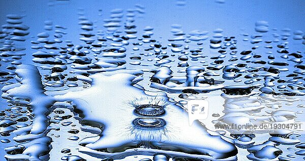 Wassertropfen fällt ins Wasser vor blauem Hintergrund