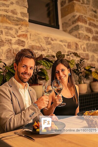 Lifestyle  ein hübsches  verliebtes junges Paar in einem Restaurant  das mit einem Glas Wein anstößt  um den Valentinstag zu feiern  vertikales Foto