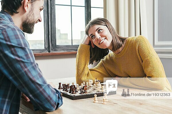 Junges Paar sitzt zusammen und spielt Schach zu Hause