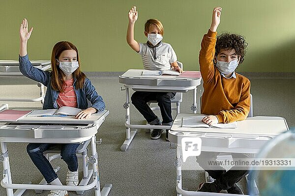 Frontansicht Kinder mit medizinischen Masken Schule heben ihre Hände