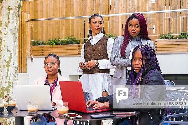 Junge und alternative Geschäftsfrauen schwarzer Ethnie. In einer Teamwork Sitzung  posieren mit Blick in die Kamera