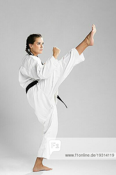 Junge erwachsene Frau mit schwarzem Gürtel  die Karate trainiert