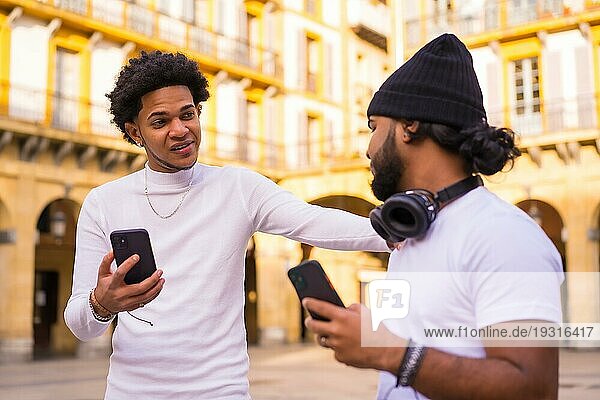 Lifestyle  zwei schwarze Latino Freunde winken  als sie sich auf der Straße treffen