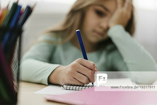 Kleines Mädchen mit Kopfschmerzen bei den Hausaufgaben