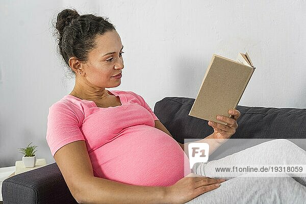 Seitenansicht schwangere Frau zu Hause lesen Couch