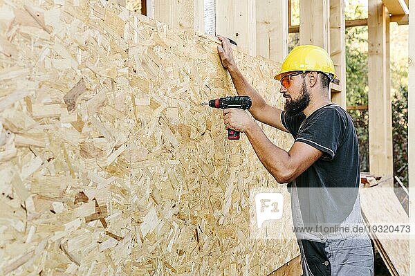 Seitenansicht Bauarbeiter beim Bohren von Sperrholz mit Kopierraum