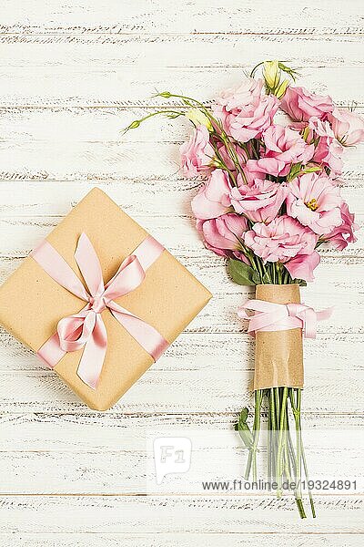 Schöner Strauß frischer rosa Eustoma Blumen mit Geschenkbox Holzoberfläche