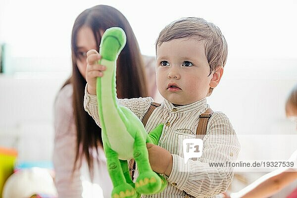 Kleiner Junge hält grünes Dinosaurier Spielzeug
