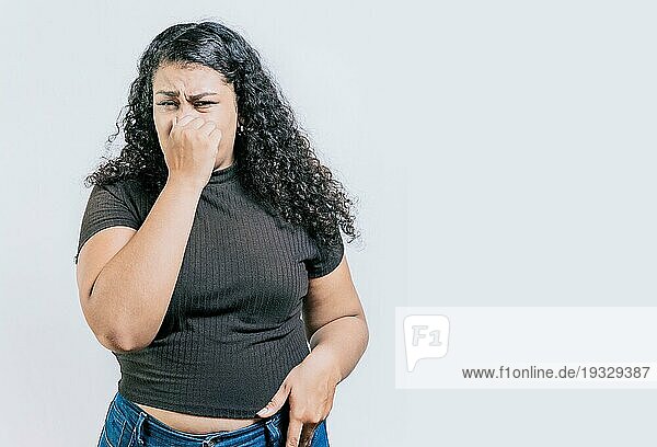 Lateinische Frau  die sich die Nase vor einem schlechten Geruch zuhält  isoliert. Unzufriedenes Mädchen hält sich isoliert die Nase zu. Angewiderte Menschen halten sich die Nase zu