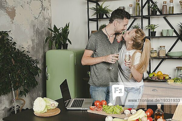 Junges Paar hält Champagnerflöte stehend Küchentisch