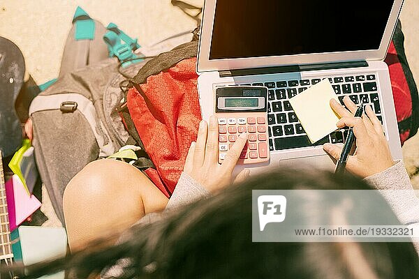 Frau macht sich Notizen von Hand mit Taschenrechner Laptop sonnigen Tag