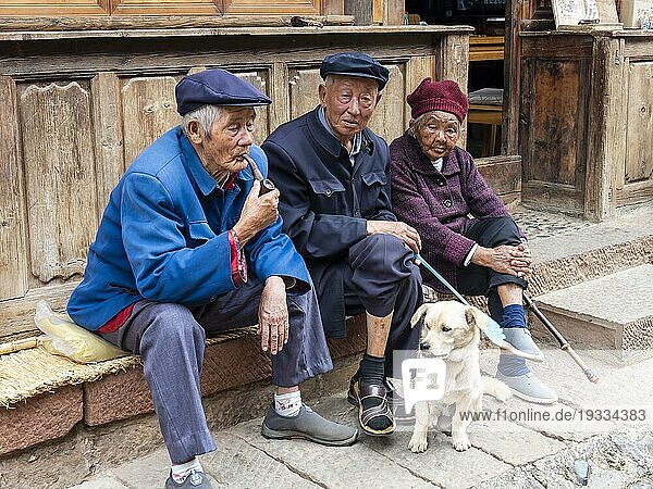Alte Menschen sitzen vor dem Haus  chinesische Rentner mit Hund  Shaxi  Yunnan  China  Asien