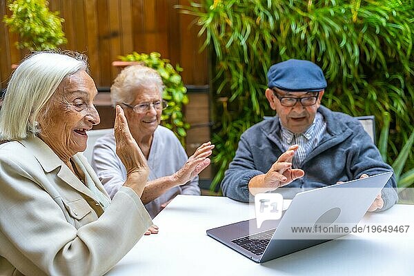 Glückliche ältere Menschen  die sich mit ihrem Laptop in einer geriatrischen Einrichtung amüsieren