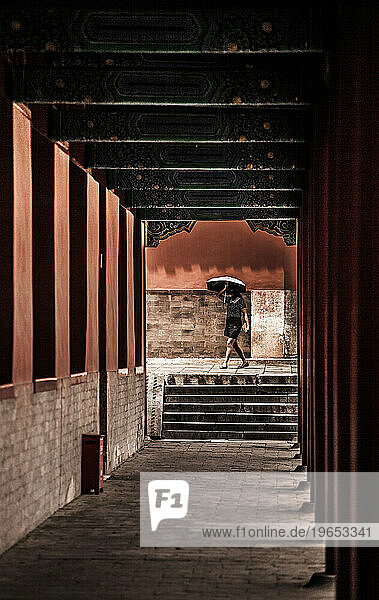 A tourist walking through a corridor in the Forbidden City