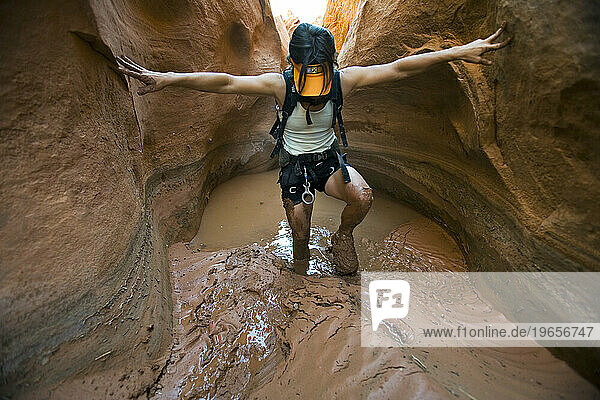 A woman hiking through mud in canyon  Utah.