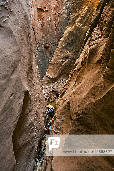 Two people canyoneering in slot canyon  Utah.