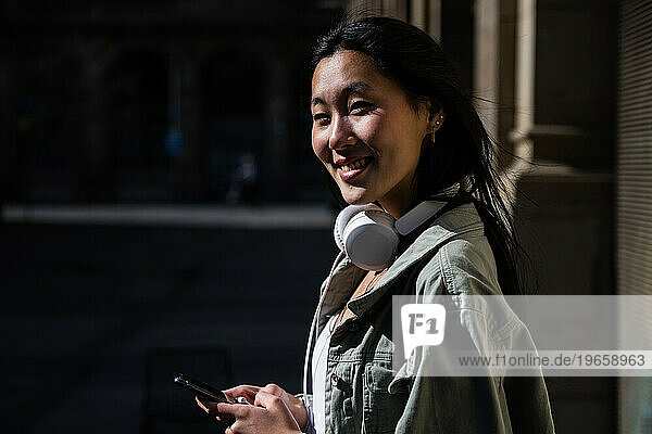 Young beautiful happy woman texting and looking at camera.