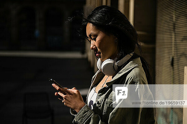 Young pretty confident woman texting and wearing headphones.