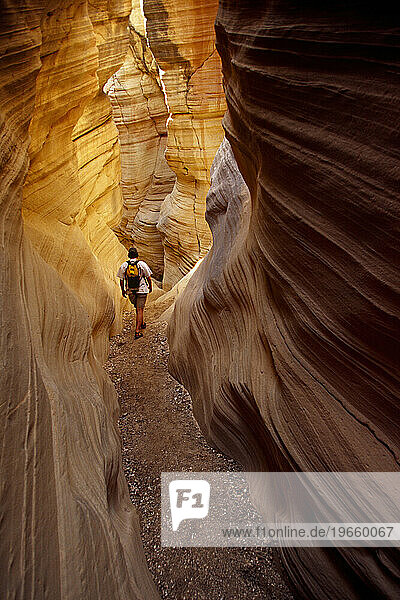 Man hiking through narrow desert canyon.