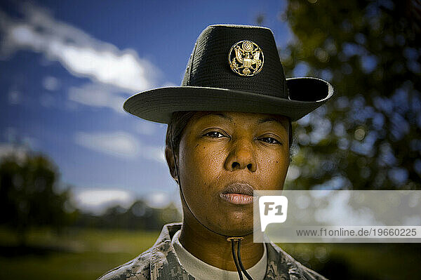 A drill sergeant wears a traditional campaign hat and camouflage uniform while looking tough.