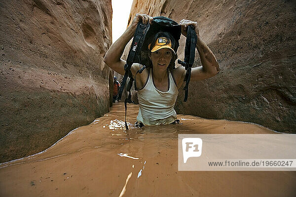 A woman wading through water in narrow canyon  Utah.