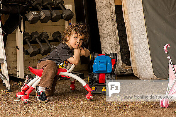 toddler boy sitting on toy outside
