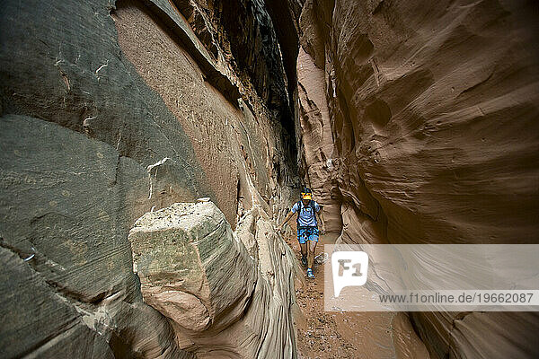 A woman hiking down slot canyon  Utah.