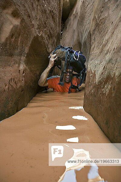 A man wading through water in narrow canyon  Utah.