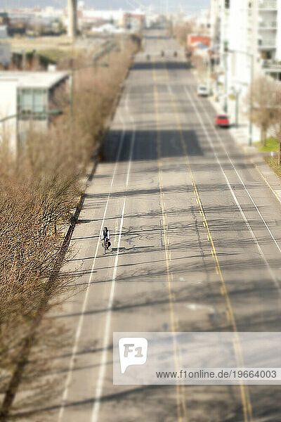 Bike commuter on an extracycle riding along a long stretch of deserted road.