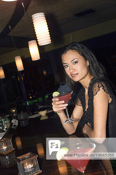 A woman at a bar with a cocktail.