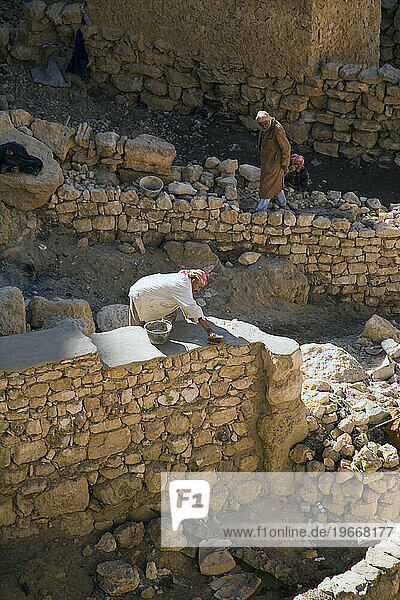 Workmen rebuild stone walls at the abandoned Berber mountain village at Chenini.