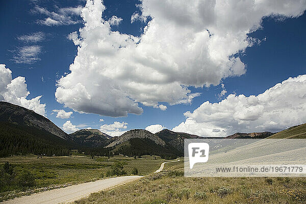 A long dirt road winds near the the foothills of the Rockies in Montana.