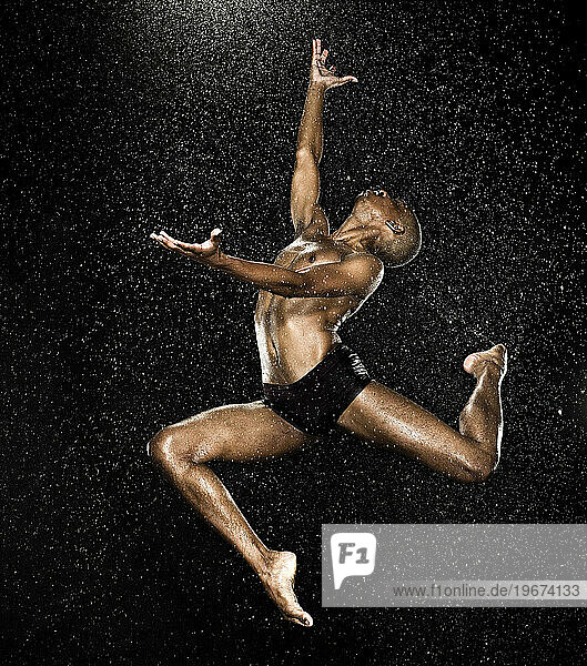 A dancer performing beautiful body controlled jumps with help from a trampoline and sometimes water.