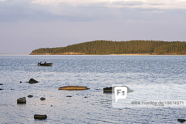 Man in boat makes his way across the waters of Lake Athabasca in Alberta  Canada.