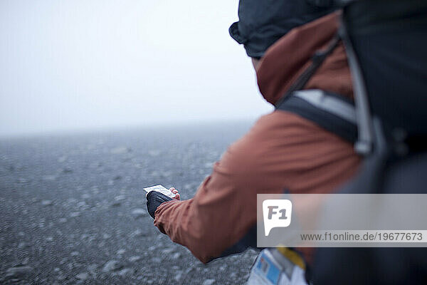 Hiker reading compass on the highlands of Iceland