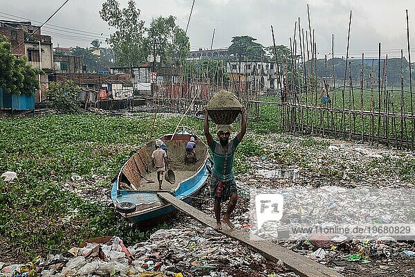 Bauarbeiter transportieren Sand aus einem Boot über eine Planke  Tel Ghat  Dhaka  Bangladesch  Asien