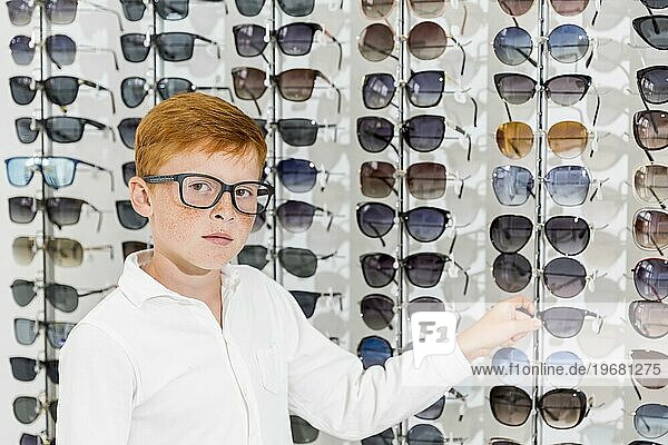 Unschuldiger Junge schaut Kamera weiß haltend Brillenoptik speichern