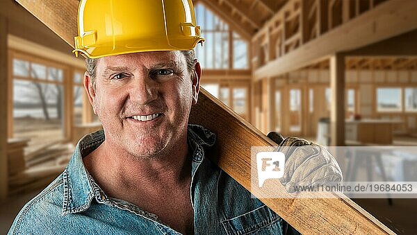Gutaussehender  freundlicher männlicher Bauunternehmer auf einer Baustelle  der einen Schutzhelm und Arbeitshandschuhe trägt
