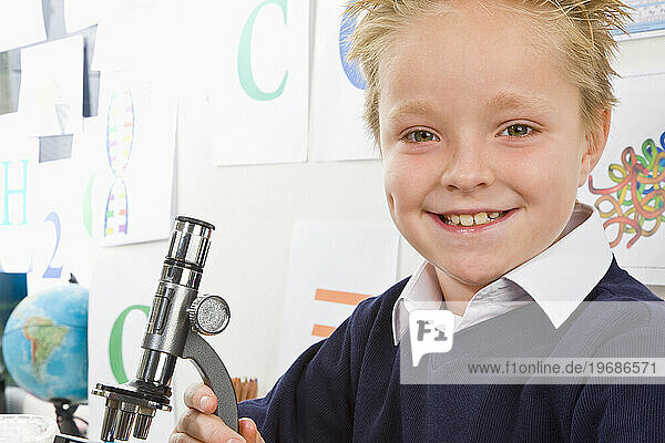 Schoolboy holding a microscope