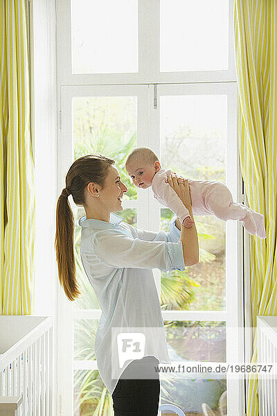 Mother Lifting Baby in Nursery