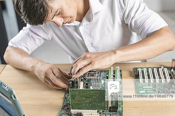 Nahaufnahme eines männlichen Technikers  der die Hauptplatine eines Computers repariert