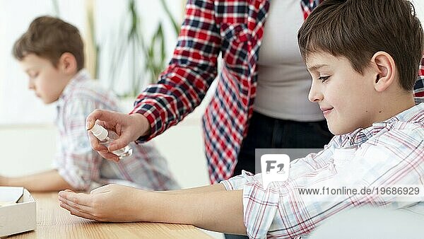 Seitenansicht Mutter sprüht Desinfektionsmittel auf die Hände des Kindes