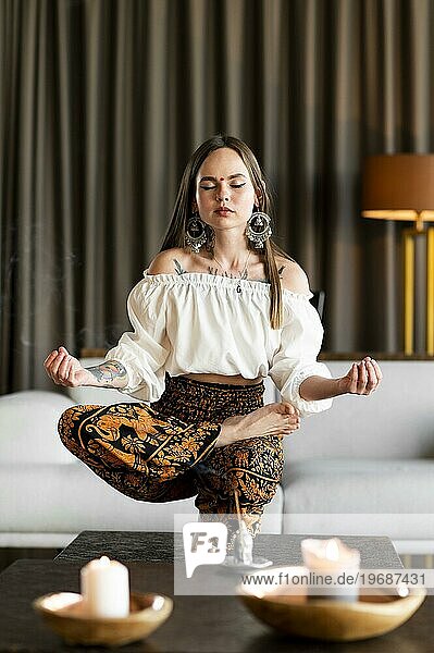 Full shot woman meditating inside